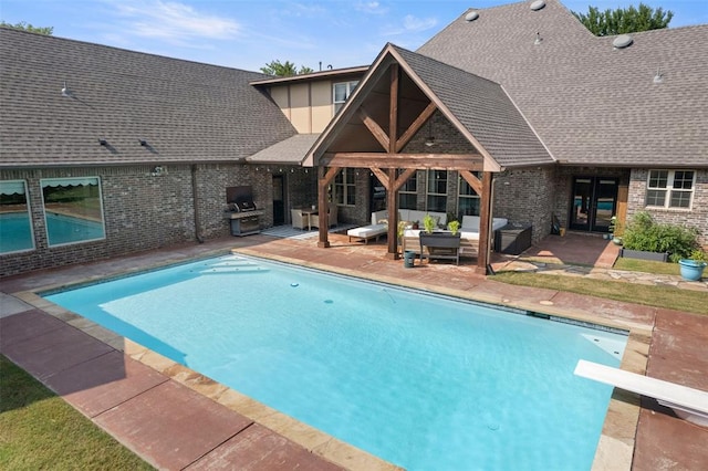 view of swimming pool featuring a diving board, an outdoor hangout area, a patio, and exterior kitchen