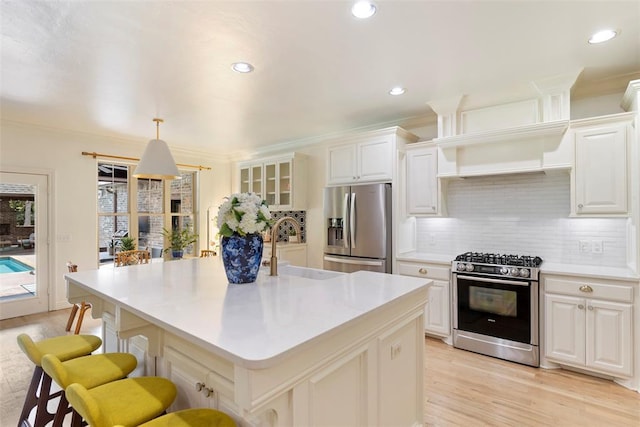 kitchen with white cabinetry, decorative light fixtures, stainless steel appliances, and an island with sink