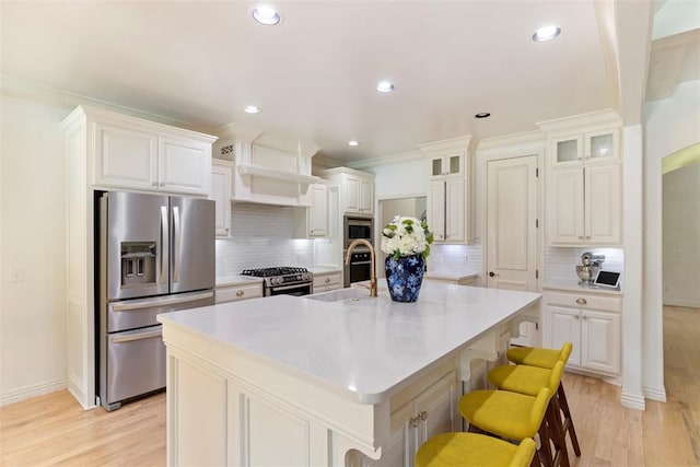 kitchen featuring an island with sink, appliances with stainless steel finishes, a breakfast bar, and sink