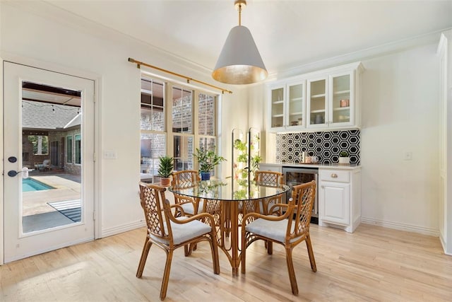 dining room with light hardwood / wood-style flooring, ornamental molding, and beverage cooler