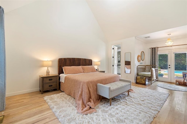 bedroom featuring access to exterior, light hardwood / wood-style flooring, high vaulted ceiling, and french doors