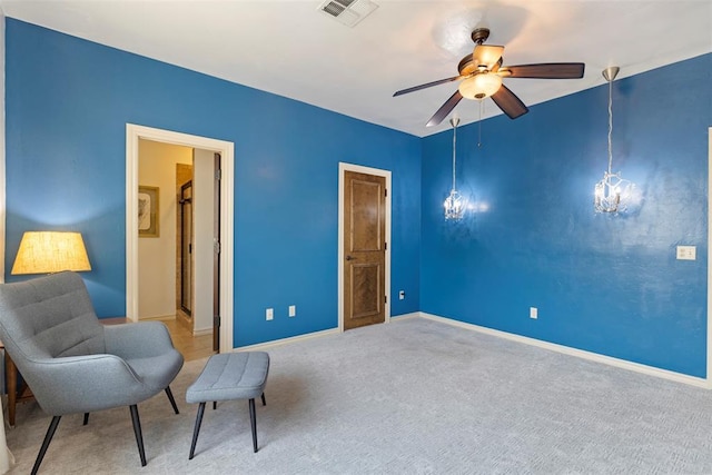 living area with ceiling fan with notable chandelier and carpet flooring