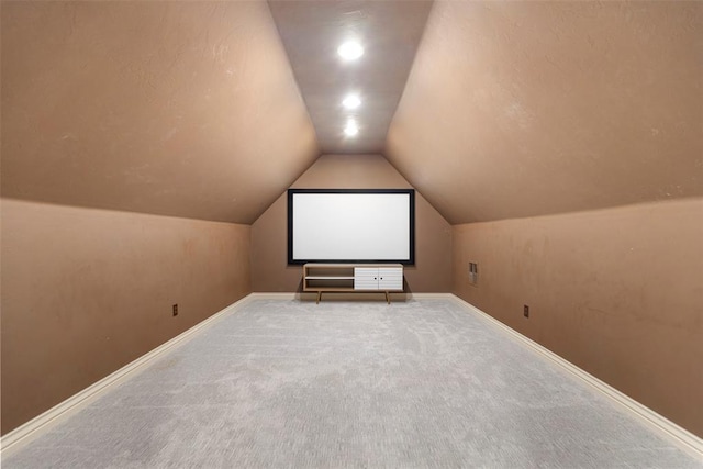 carpeted home theater featuring lofted ceiling