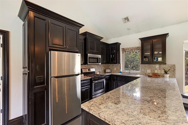 kitchen with vaulted ceiling, sink, decorative backsplash, stainless steel appliances, and light stone countertops