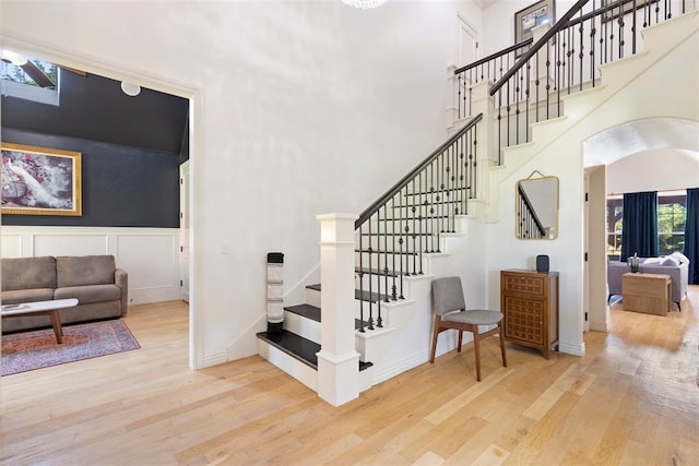 stairs with a towering ceiling, arched walkways, and wood finished floors