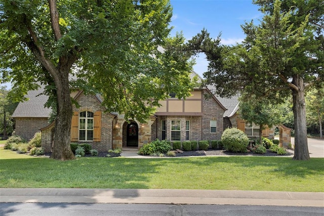 tudor home featuring brick siding and a front yard