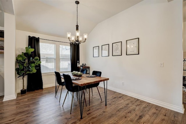 dining area featuring dark wood-type flooring, lofted ceiling, and an inviting chandelier