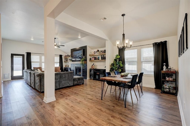 dining space featuring vaulted ceiling, ceiling fan with notable chandelier, and light hardwood / wood-style flooring