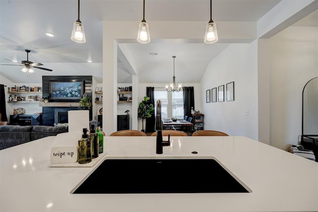 kitchen with ceiling fan with notable chandelier, sink, vaulted ceiling, and hanging light fixtures