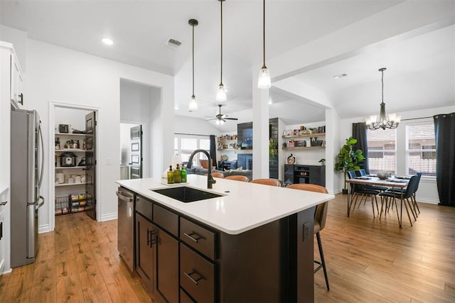 kitchen with appliances with stainless steel finishes, light hardwood / wood-style floors, sink, and a center island with sink