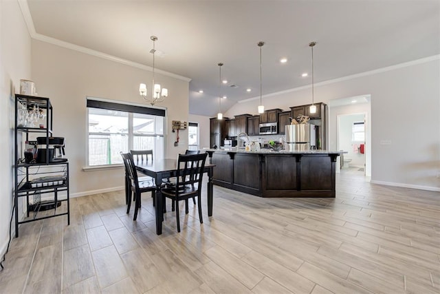 dining area featuring vaulted ceiling, ornamental molding, and a notable chandelier