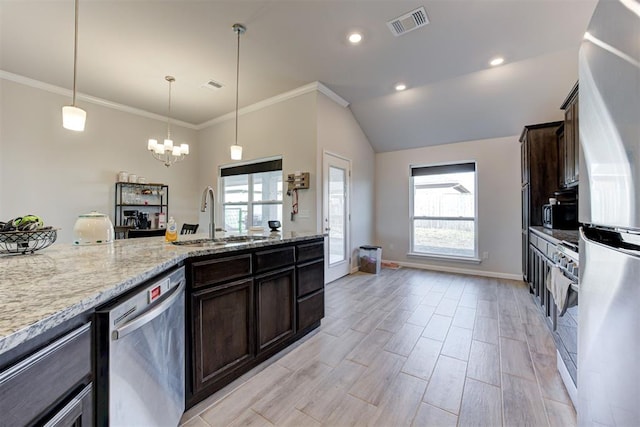 kitchen with sink, hanging light fixtures, light stone countertops, stainless steel appliances, and dark brown cabinets