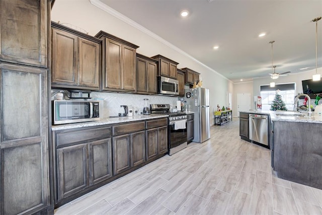 kitchen featuring dark brown cabinetry, appliances with stainless steel finishes, sink, ceiling fan, and crown molding