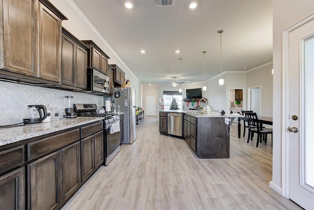 kitchen with decorative light fixtures, ceiling fan, appliances with stainless steel finishes, dark brown cabinets, and light stone counters