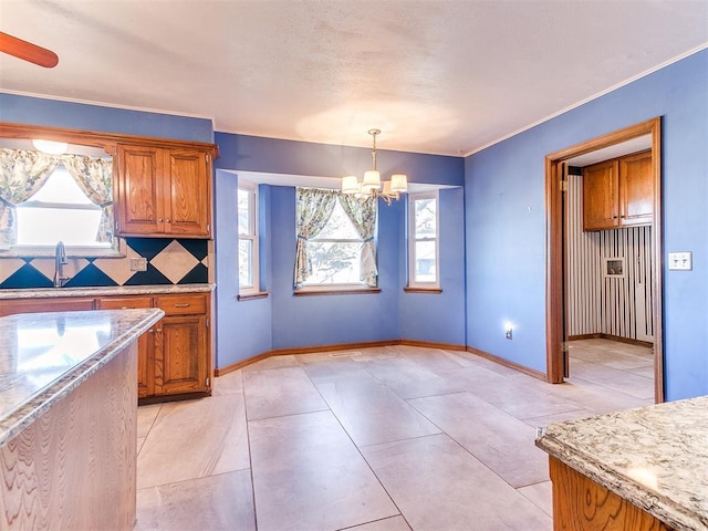 kitchen with decorative light fixtures, backsplash, a wealth of natural light, and a chandelier