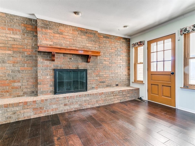 unfurnished living room with a brick fireplace, dark hardwood / wood-style floors, and crown molding