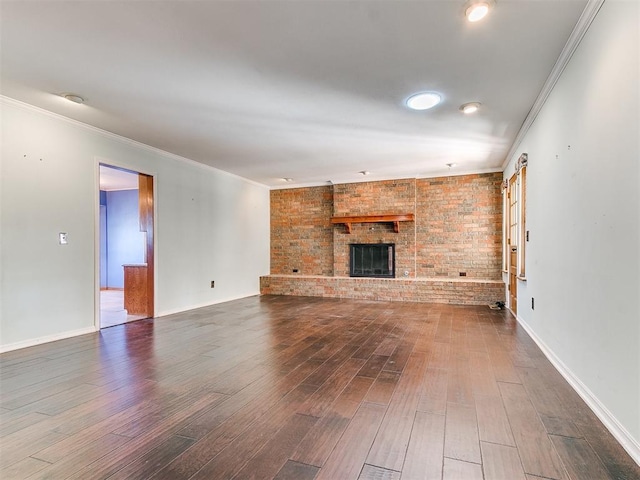 unfurnished living room featuring a brick fireplace, crown molding, and dark hardwood / wood-style floors