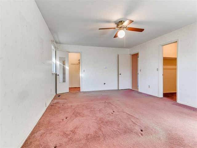 unfurnished bedroom featuring a spacious closet, ceiling fan, carpet, and a closet