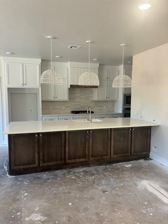 kitchen featuring decorative light fixtures, double oven, concrete floors, and white cabinets