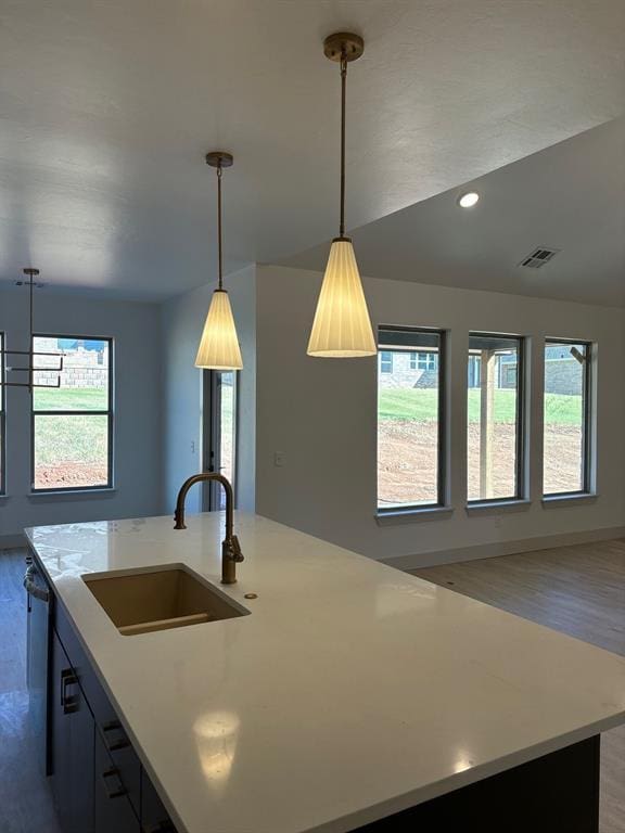 kitchen featuring an island with sink, sink, hanging light fixtures, and plenty of natural light