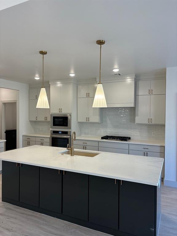 kitchen with appliances with stainless steel finishes, a large island, and sink