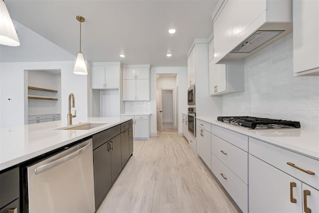 kitchen featuring sink, hanging light fixtures, stainless steel appliances, custom range hood, and white cabinets