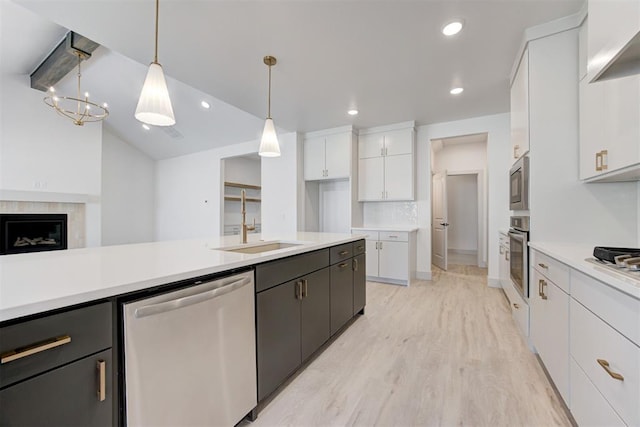 kitchen featuring lofted ceiling, sink, white cabinetry, stainless steel appliances, and decorative light fixtures