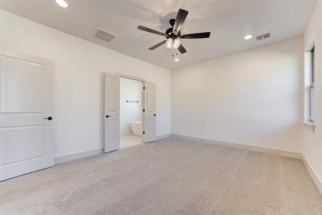 unfurnished bedroom featuring ceiling fan, light colored carpet, and connected bathroom