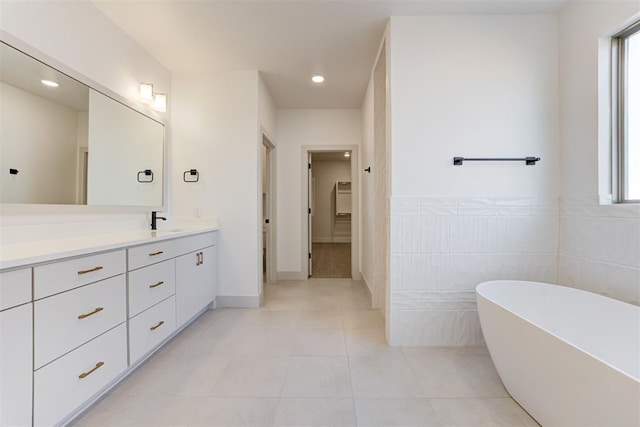 bathroom with tile patterned flooring, vanity, tile walls, and a bathtub