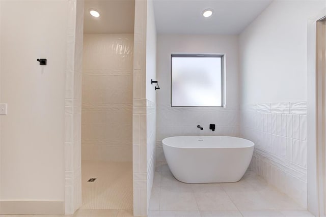 bathroom with tile patterned flooring, separate shower and tub, and tile walls