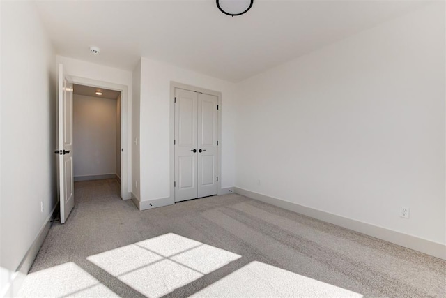 unfurnished bedroom with light carpet and a closet