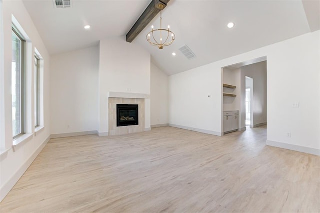 unfurnished living room with a tiled fireplace, vaulted ceiling with beams, a notable chandelier, and light hardwood / wood-style floors