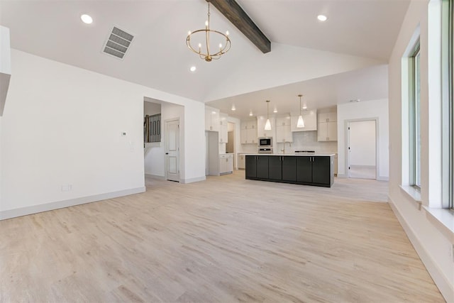 unfurnished living room with high vaulted ceiling, plenty of natural light, a notable chandelier, beamed ceiling, and light hardwood / wood-style floors