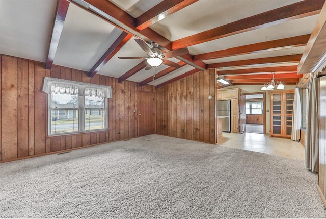 unfurnished room with wooden walls, light colored carpet, and a healthy amount of sunlight