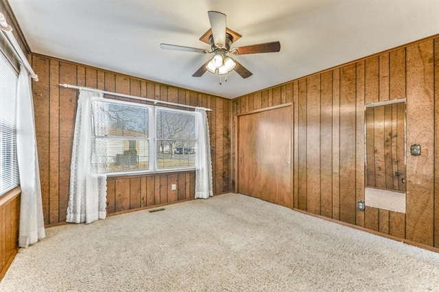 spare room with carpet floors, ceiling fan, and wood walls