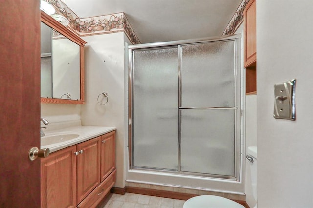 bathroom with vanity, a shower with door, and toilet