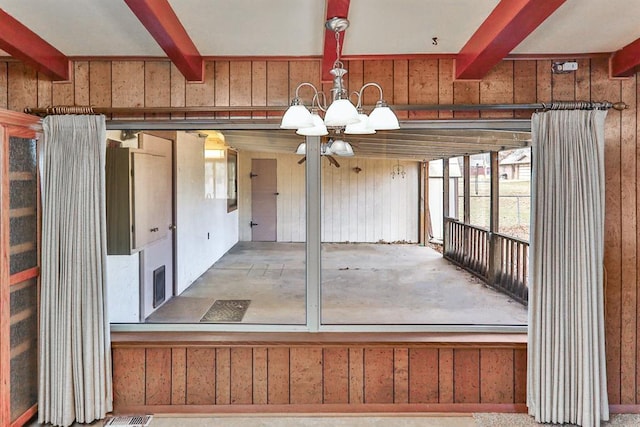 misc room with an inviting chandelier, beam ceiling, and wood walls