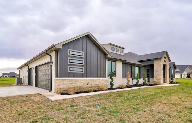 view of front of home featuring central AC unit, a garage, and a front yard