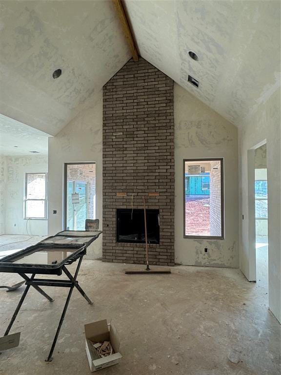 unfurnished living room with a brick fireplace, a wealth of natural light, and high vaulted ceiling