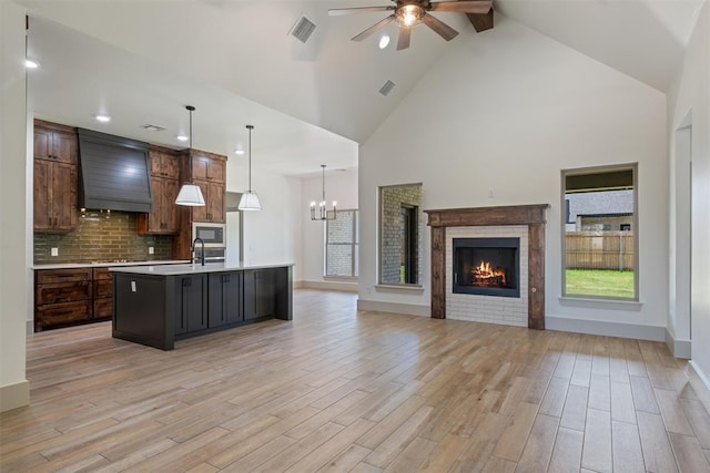 kitchen featuring dark brown cabinets, an island with sink, ceiling fan with notable chandelier, and light hardwood / wood-style flooring