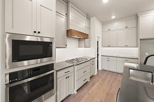 kitchen with light hardwood / wood-style floors, white cabinets, appliances with stainless steel finishes, and sink