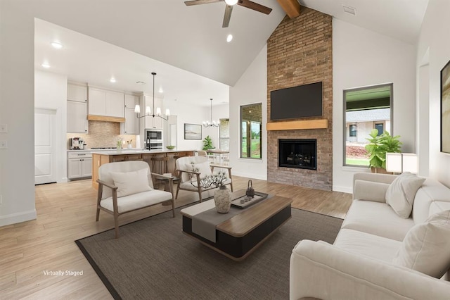 living room featuring light wood-style floors, high vaulted ceiling, ceiling fan with notable chandelier, recessed lighting, and beamed ceiling