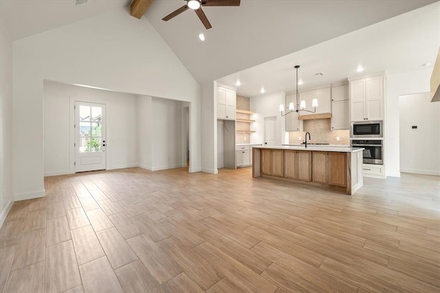 kitchen featuring oven, open floor plan, built in microwave, and ceiling fan with notable chandelier