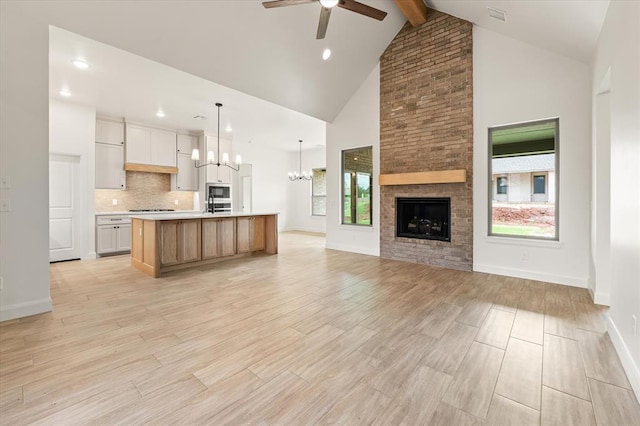 kitchen featuring light countertops, high vaulted ceiling, ceiling fan with notable chandelier, open floor plan, and beamed ceiling