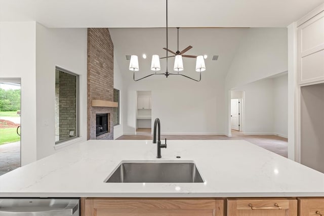 kitchen featuring light stone counters, a sink, dishwashing machine, and open floor plan