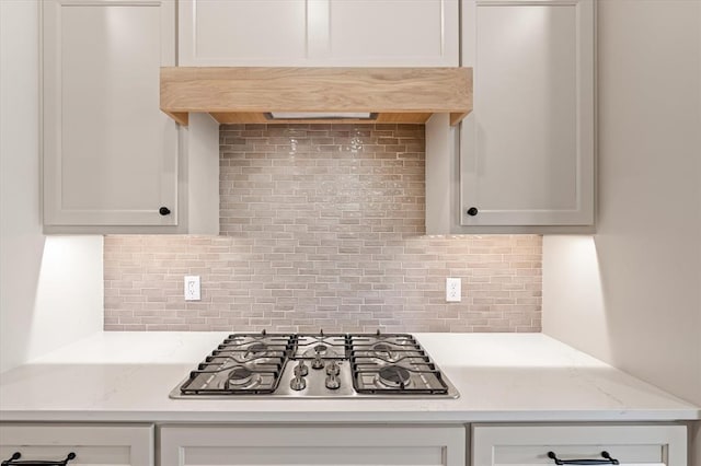 kitchen featuring stainless steel gas stovetop, decorative backsplash, and white cabinetry