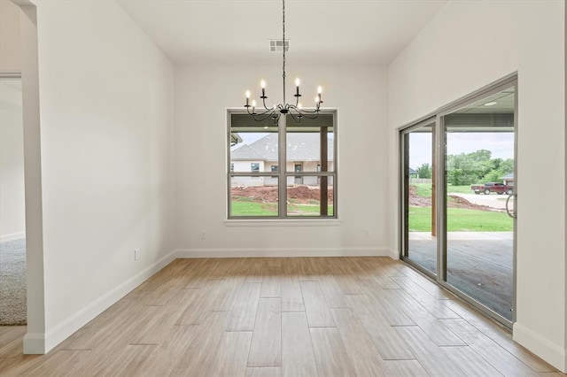 unfurnished dining area with baseboards, visible vents, light wood-style flooring, and a notable chandelier