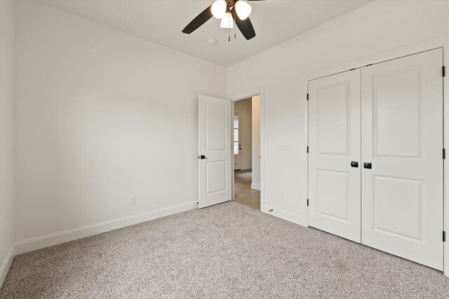 unfurnished bedroom featuring carpet floors, baseboards, ceiling fan, and a closet
