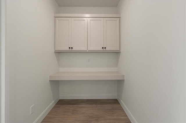 unfurnished office featuring baseboards and wood finished floors