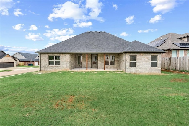 rear view of property featuring a lawn, brick siding, fence, and a patio